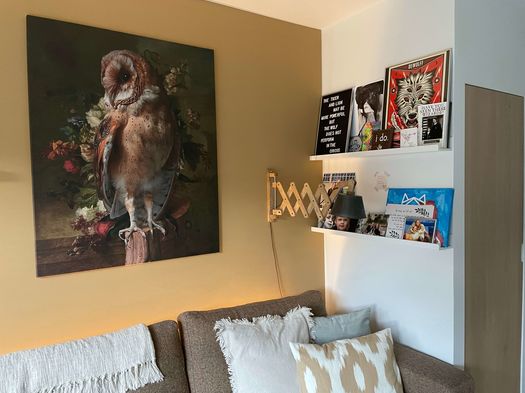 grote foto schilderij van uil met bloemen aan gele muur