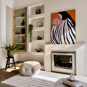 Moderne woonkamer met wit meubilair, gouden accenten en kleurrijk kunstwerk