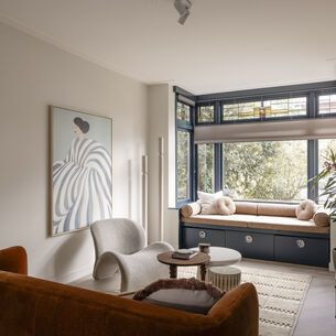 Moderne woonkamer met zitnis, fluwelen bank, crèmekleurige stoelen en abstract kunst