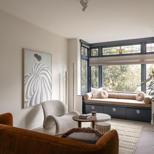 Moderne woonkamer met zitnis, fluwelen bank, crèmekleurige stoelen en abstract kunst