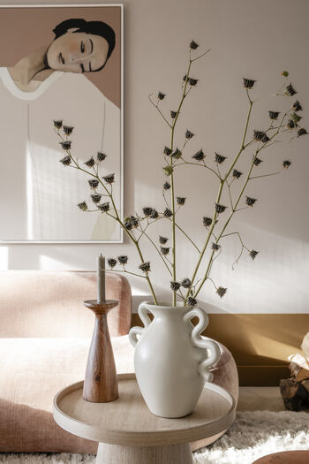 Styling detail met witte vaas, gedroogde takken, kaarshouder en portret van vrouw