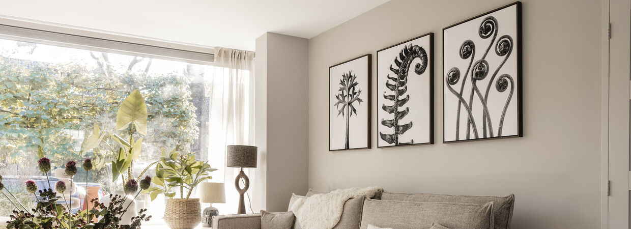 Sfeervolle woonkamer met beige bank, houten accenten en botanische kunst in zwart-wit