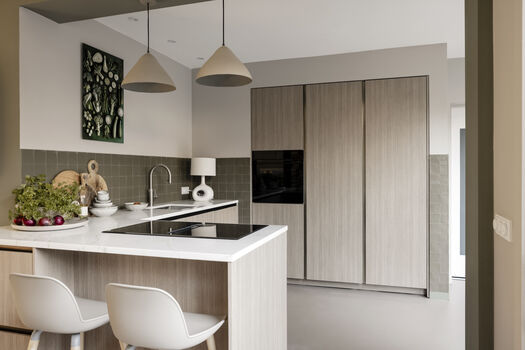 Lichte keuken met houten fronten, kookeiland en groen kunstwerk aan de muur