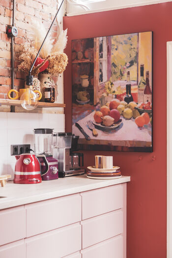 Keuken met rode muur, schilderij van stilleven met fruit en wijn, en retro keukenapparatuur