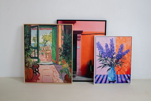 Drie ArtFrame™ kunstwerken tegen witte muur: landschap, abstract en bloemen in vaas