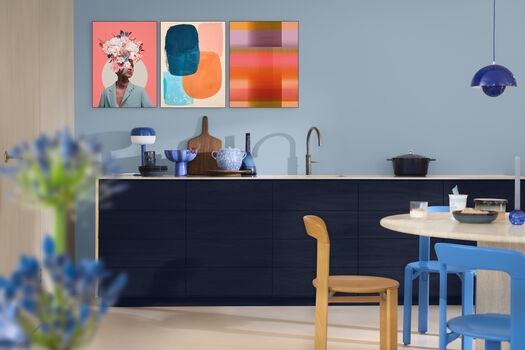 Eetkamer met muur geverfd in Mellow Flow, en drie kleurrijke kunstwerken op een rij