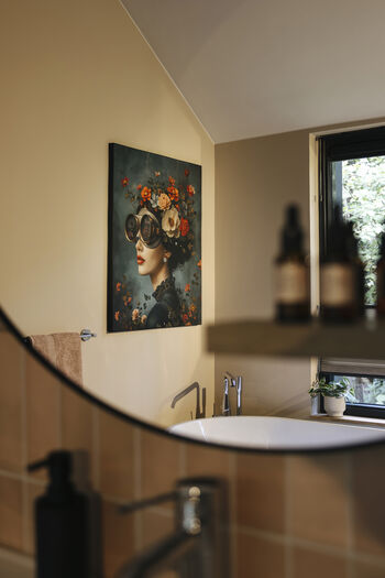 Moderne badkamer met rond bad, klassiek portret aan muur en warm beige kleurenschema.