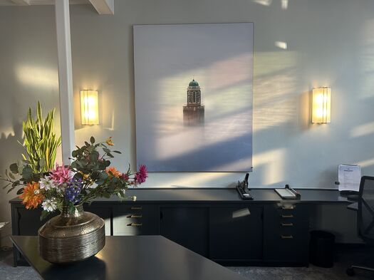 Receptiebalie met grote foto aan de muur en bloemen op de balie.
