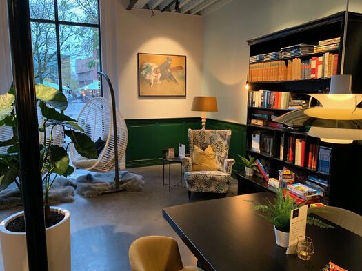 Gezellige kantoorhoek met boekenkast, hangstoel en sfeervolle verlichting.