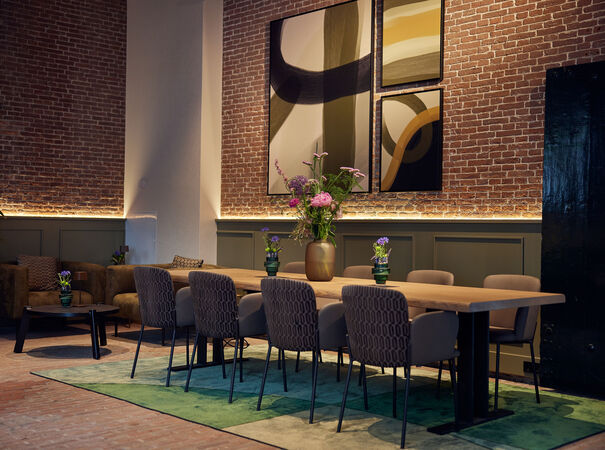 Moderne vergaderruimte met grote houten tafel, designstoelen en abstracte kunst.