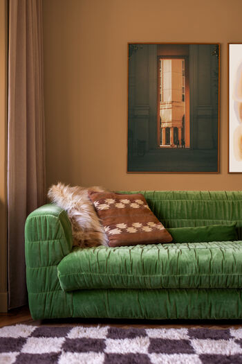 Groene bank met architectuurfoto op Sahara Vibe muur, warme bruintinten interieur