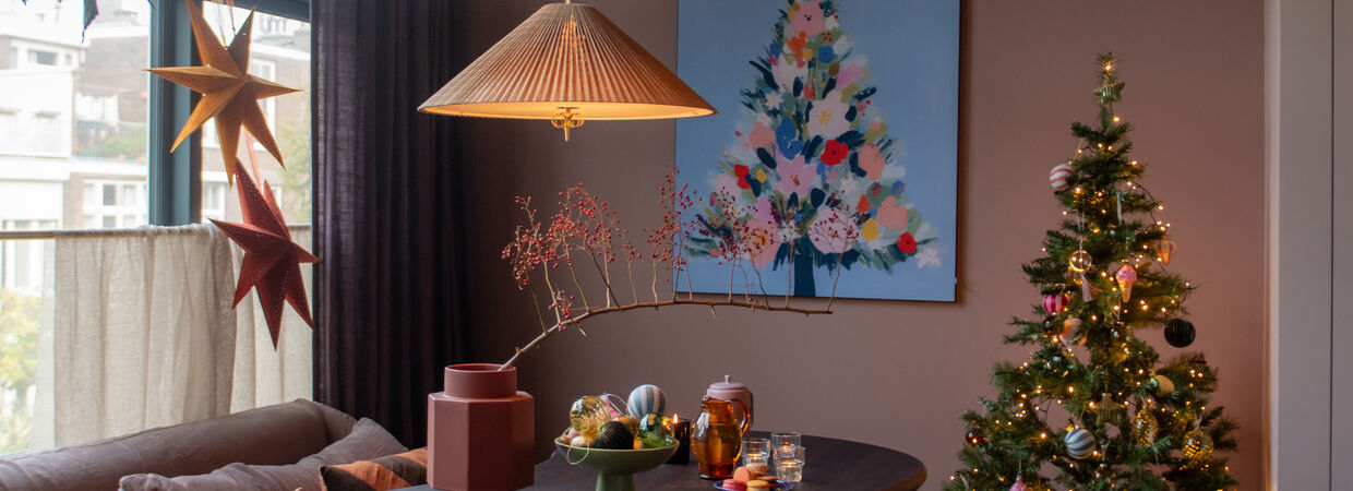Gezellige woonkamer met kerstboom, bloemen schilderij en bruine hanglamp