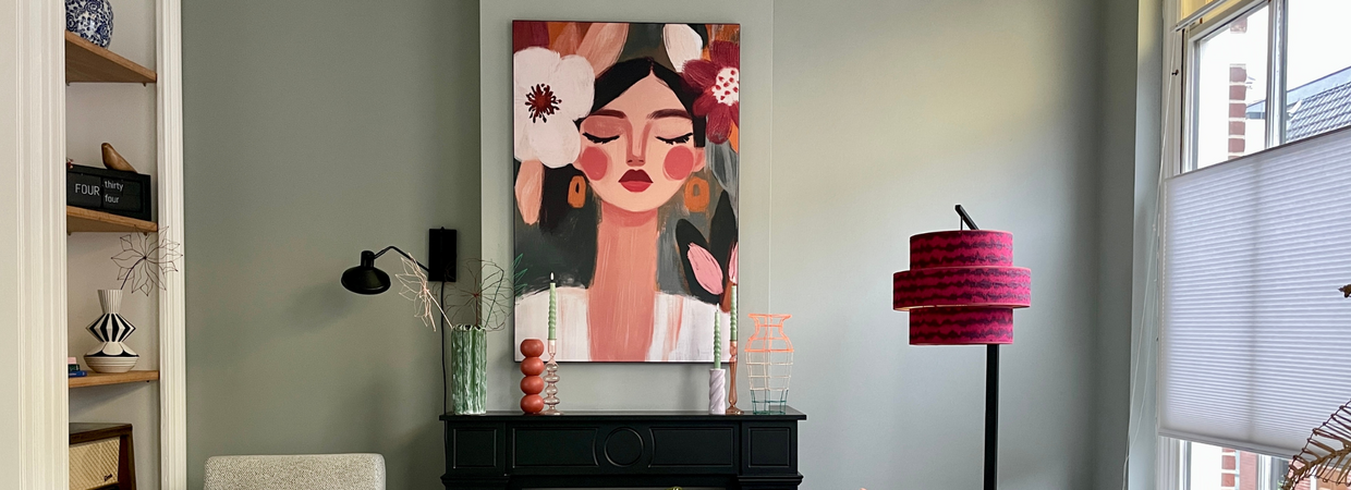 Eetkamer met groen-grijze muur en kleurrijk portret van vrouw met bloemen