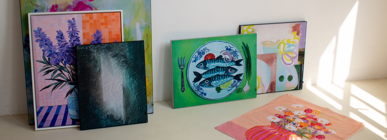 Kleurrijke kunstwerken op verschillende materialen tegen witte muur