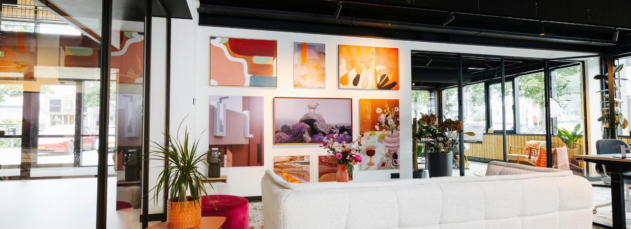Kantoorruimte met galleriewand vol kleurrijke kunstwerken en abstracte prints