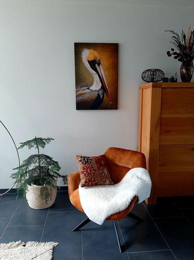oranje kunstwerk van exotische vogel aan de muur