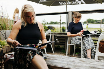 Gasten op het terras die het Werk aan de Muur tafelboek lezen
