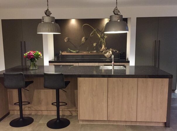 Moderne keuken met houten eiland, zwart blad, industriële lampen en kunstwerk