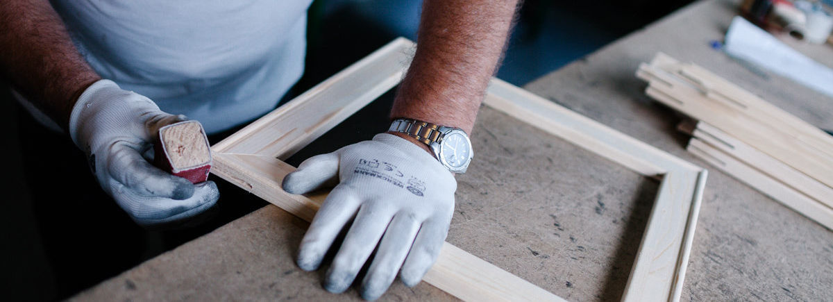 Man sanding an art frame from wood