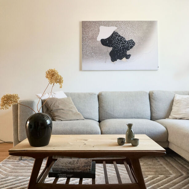 zwart wit japandi schilderij aan de muur boven grijze bank