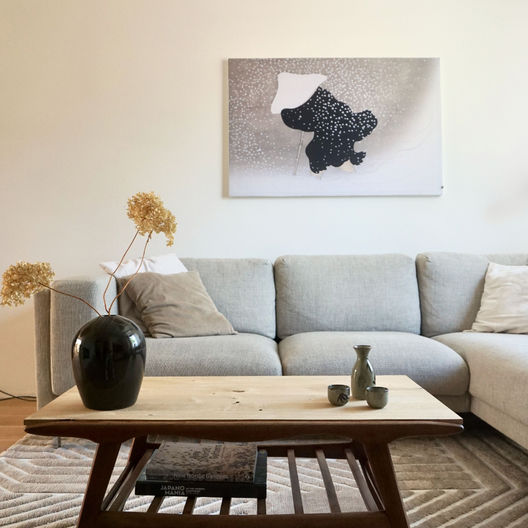 zwart wit japandi schilderij aan de muur boven grijze bank