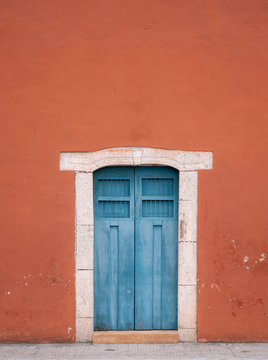 Blue door in a terracotta coloured wall from Mexico