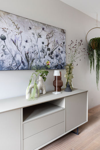 rechthoekig bloemen kunstwerk aan de muur boven tafel met planten